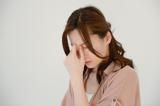 目頭を押さえる女性の写真